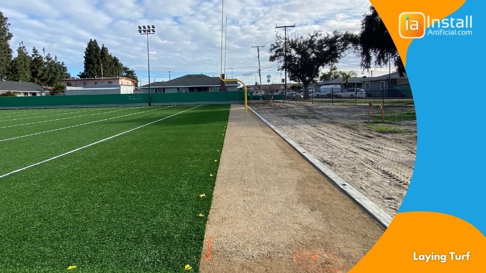 Laying artificial sports turf on the base of the field during installation